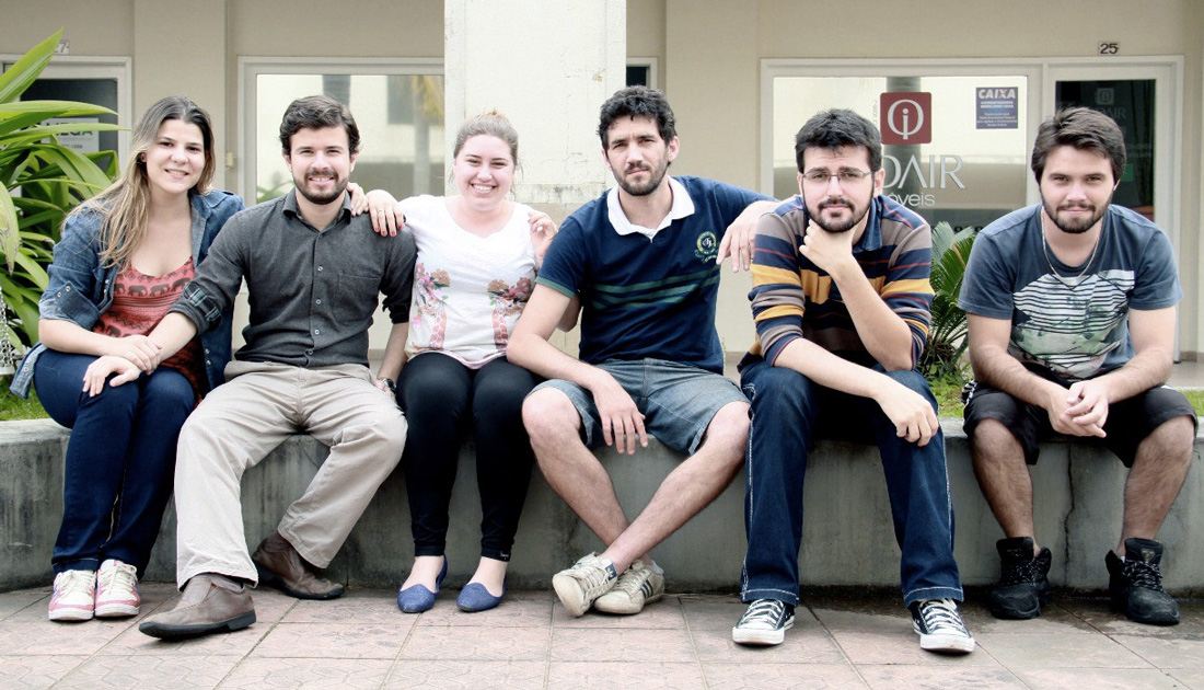 Equipe do Pé de Nuvem sentada em frente a um prédio, em outubro de 2013