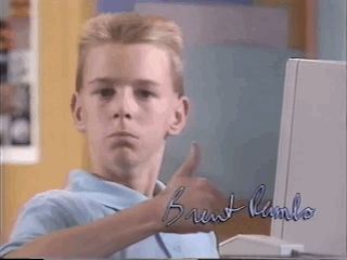 Menino fazendo sinal de positivo em frente a um computador